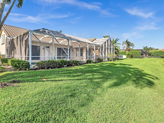 rear view of house with a lawn and a lanai