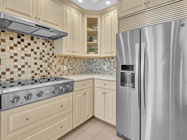 kitchen featuring backsplash, appliances with stainless steel finishes, cream cabinetry, and light tile patterned floors