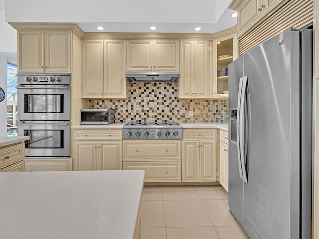 kitchen featuring appliances with stainless steel finishes, light tile patterned flooring, cream cabinets, and tasteful backsplash