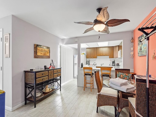 dining area featuring light wood-type flooring, a skylight, and ceiling fan