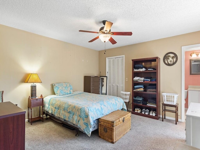 carpeted bedroom featuring a textured ceiling, a closet, ceiling fan, and connected bathroom