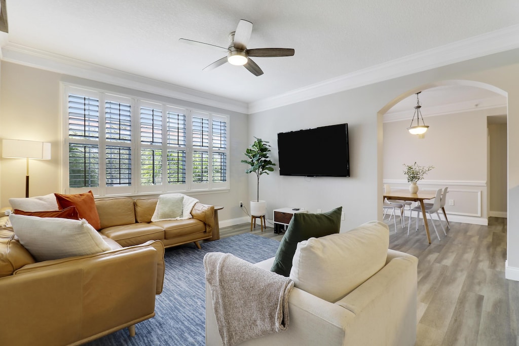 living room with crown molding, ceiling fan, and light hardwood / wood-style floors