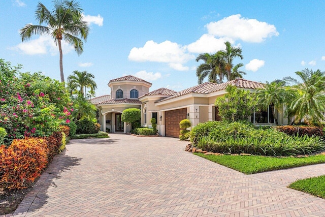 mediterranean / spanish home with stucco siding, a tile roof, decorative driveway, and a garage