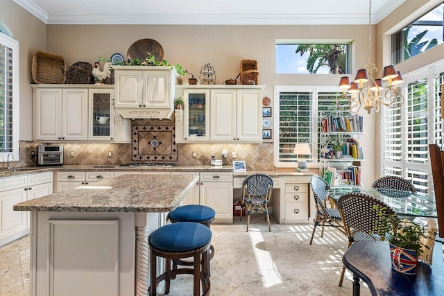 kitchen with pendant lighting, light stone counters, tasteful backsplash, and a center island