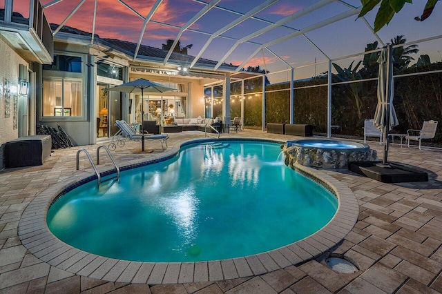 pool at dusk featuring an in ground hot tub, an outdoor living space, a patio area, and glass enclosure