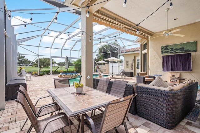 view of patio with an outdoor living space, ceiling fan, and glass enclosure