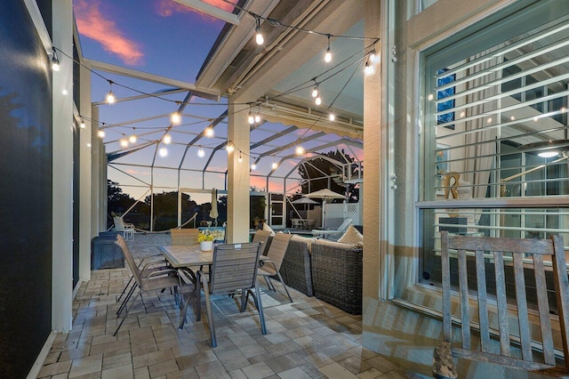 patio terrace at dusk with an outdoor living space and a lanai