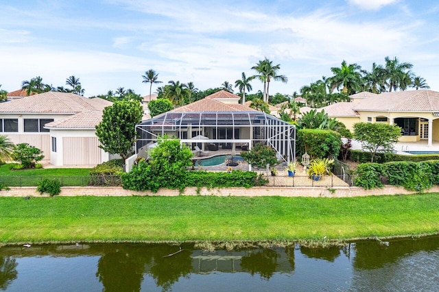 back of property with a lawn, a water view, and glass enclosure