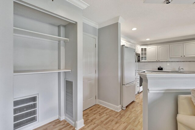 kitchen featuring backsplash, ornamental molding, white fridge, sink, and stove