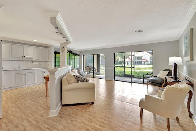 living room featuring sink, a textured ceiling, light tile patterned floors, and crown molding