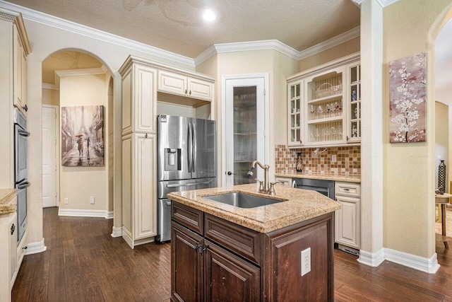 kitchen with sink, stainless steel appliances, dark brown cabinetry, light stone countertops, and an island with sink