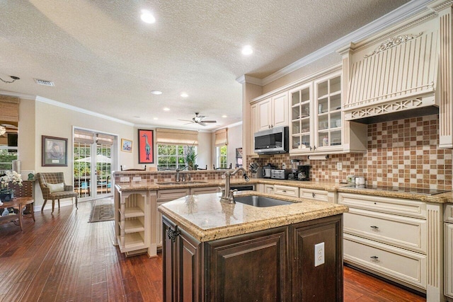 kitchen featuring sink, dark hardwood / wood-style flooring, a kitchen island with sink, kitchen peninsula, and black electric cooktop