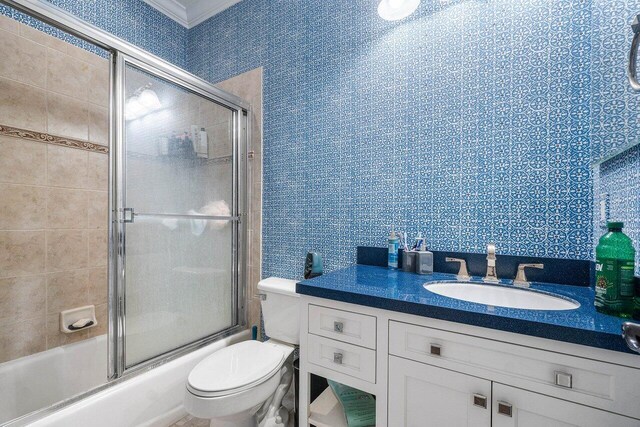 full bathroom featuring vanity, shower / bath combination with glass door, and toilet