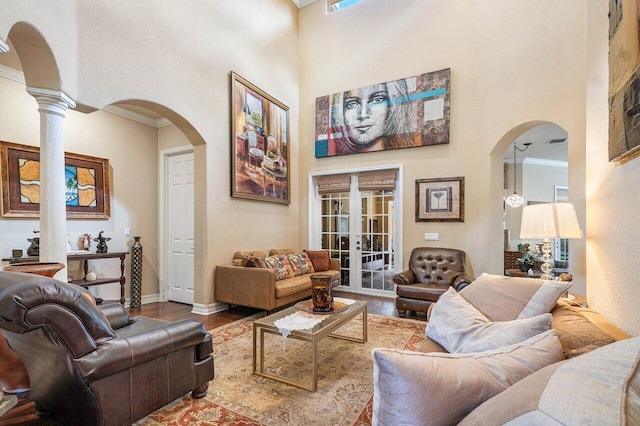 living room featuring a high ceiling, crown molding, hardwood / wood-style floors, and french doors