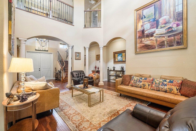 living room featuring dark hardwood / wood-style flooring, a high ceiling, and ornate columns