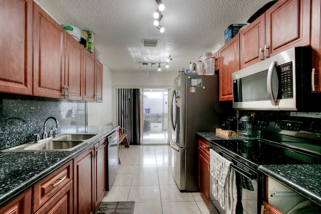 kitchen featuring stainless steel appliances, a textured ceiling, track lighting, sink, and light tile patterned flooring