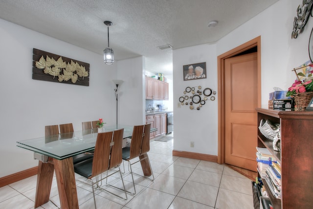 tiled dining space featuring sink and a textured ceiling