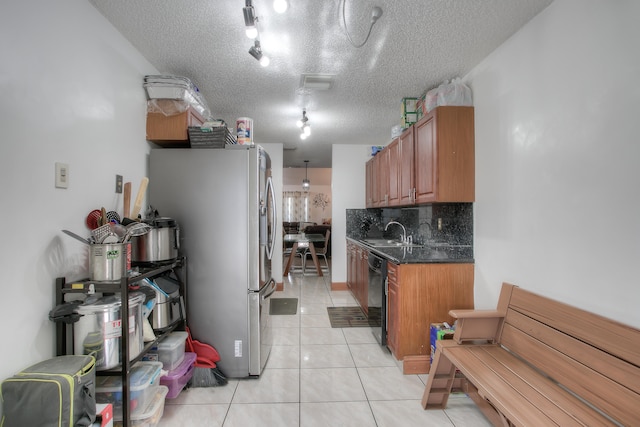 kitchen with a textured ceiling, stainless steel fridge, black dishwasher, dark stone counters, and decorative backsplash