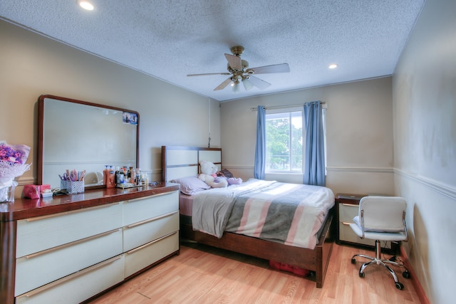 bedroom featuring ceiling fan, a textured ceiling, and light hardwood / wood-style floors