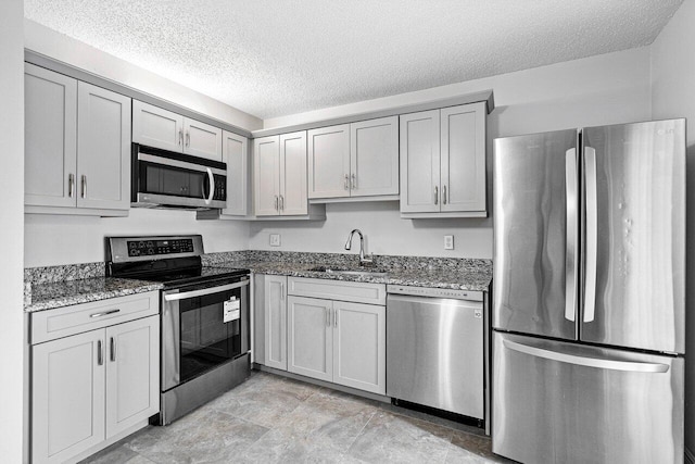 kitchen featuring sink, appliances with stainless steel finishes, stone counters, light tile patterned floors, and gray cabinets