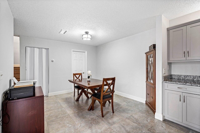 dining room with baseboards and a textured ceiling