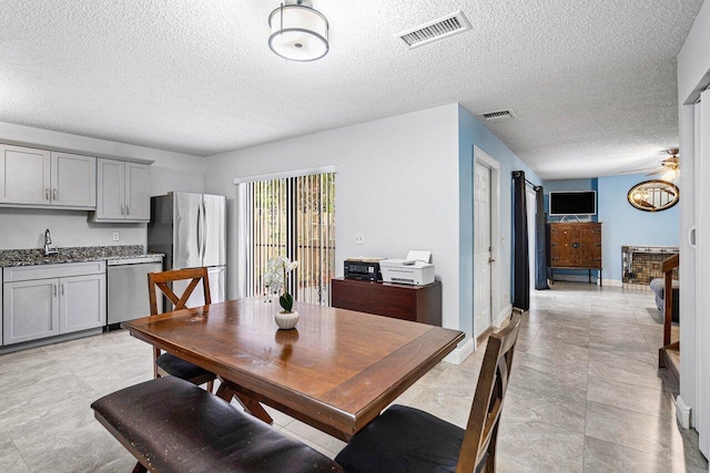 dining room with baseboards, a fireplace, visible vents, and ceiling fan