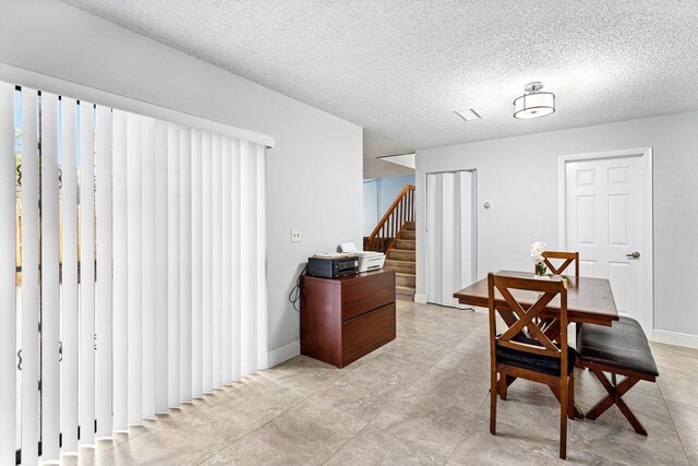 dining space with a textured ceiling and light tile patterned flooring