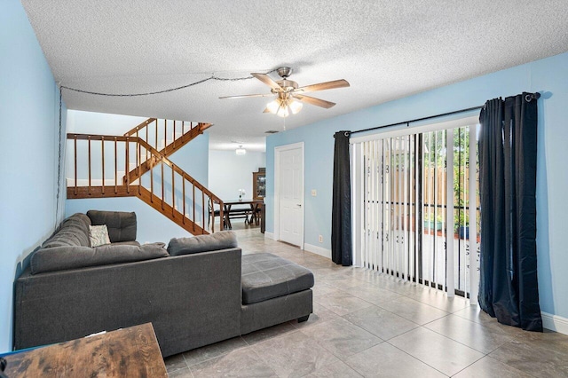 living area featuring stairs, ceiling fan, a textured ceiling, and baseboards