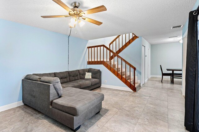 tiled living room with ceiling fan and a textured ceiling