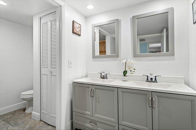 bathroom with tile patterned flooring, toilet, and dual vanity