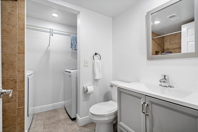 bathroom featuring tile patterned flooring, toilet, vanity, and washing machine and clothes dryer