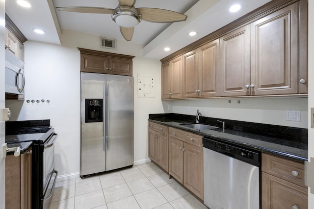 kitchen featuring stainless steel appliances, ceiling fan, sink, dark stone countertops, and light tile patterned flooring