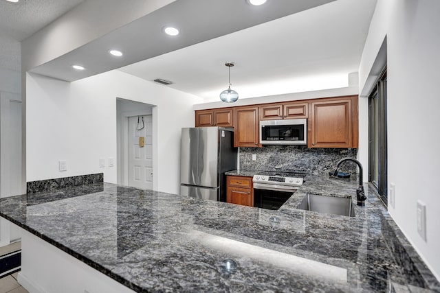 kitchen featuring dark stone counters, sink, decorative backsplash, stainless steel appliances, and kitchen peninsula