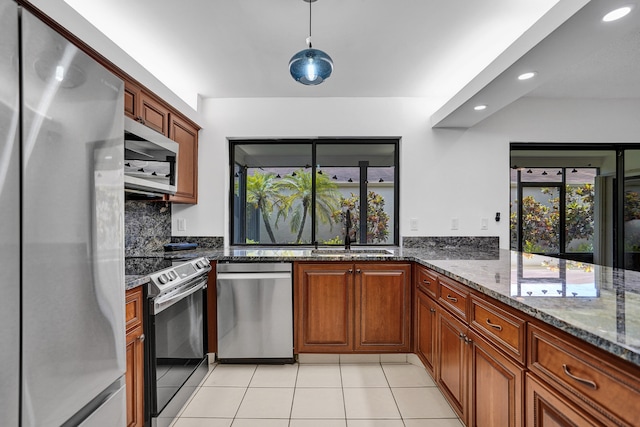 kitchen with dark stone counters, sink, decorative backsplash, light tile patterned floors, and stainless steel appliances