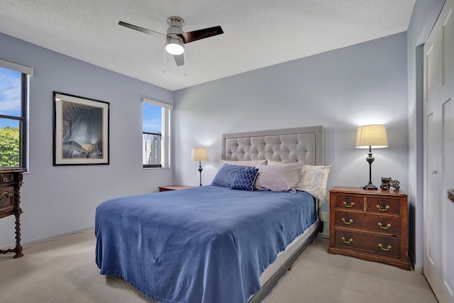 bedroom featuring ceiling fan, a textured ceiling, and light carpet