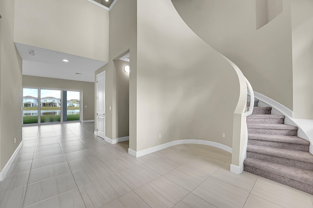 staircase featuring tile patterned flooring and a towering ceiling