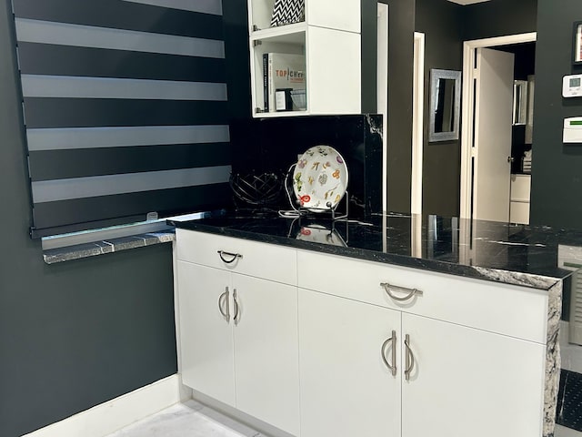 interior space featuring white cabinets and dark stone countertops