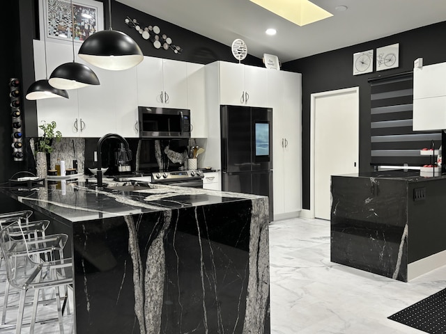 kitchen with white cabinets, black refrigerator, dark stone countertops, and pendant lighting