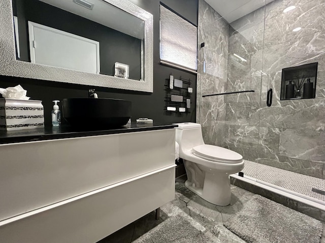 bathroom featuring vanity, toilet, and a tile shower