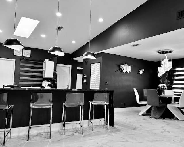 kitchen with pendant lighting, lofted ceiling with skylight, and a breakfast bar area