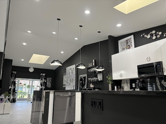 kitchen with backsplash, stainless steel dishwasher, vaulted ceiling with skylight, pendant lighting, and white cabinetry