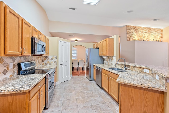 kitchen with tasteful backsplash, appliances with stainless steel finishes, light tile patterned floors, sink, and kitchen peninsula