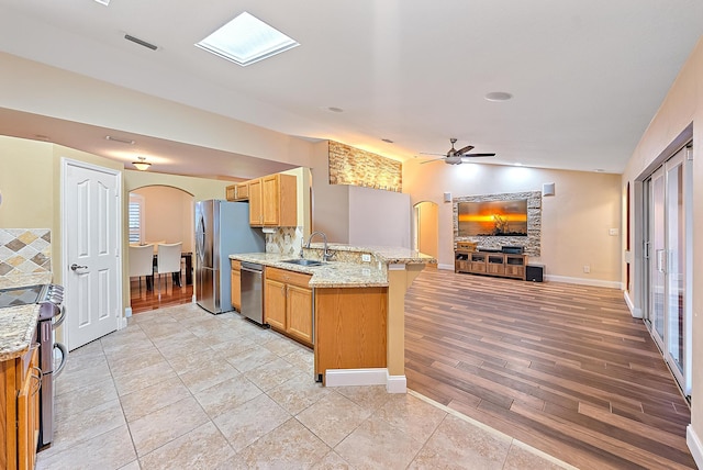 kitchen with sink, appliances with stainless steel finishes, light hardwood / wood-style flooring, light stone countertops, and vaulted ceiling