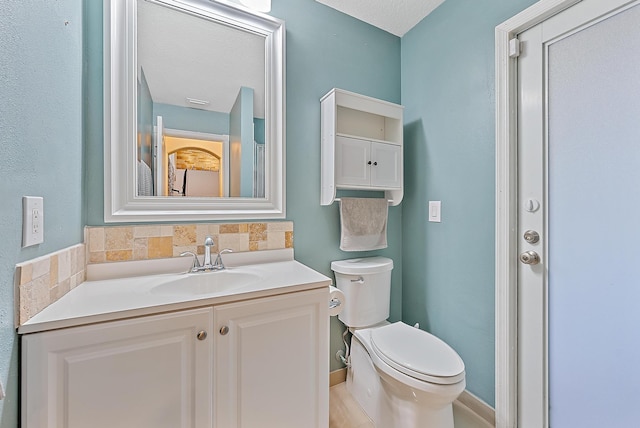 bathroom with backsplash, a textured ceiling, vanity, and toilet