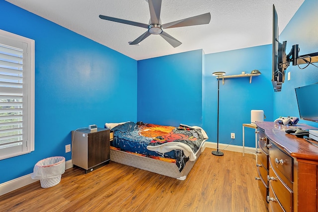 bedroom featuring light hardwood / wood-style floors, ceiling fan, and a textured ceiling