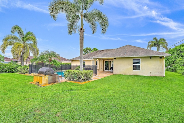 rear view of house featuring a fenced in pool and a lawn