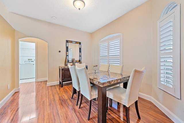 dining space with hardwood / wood-style floors, washer / clothes dryer, and a healthy amount of sunlight