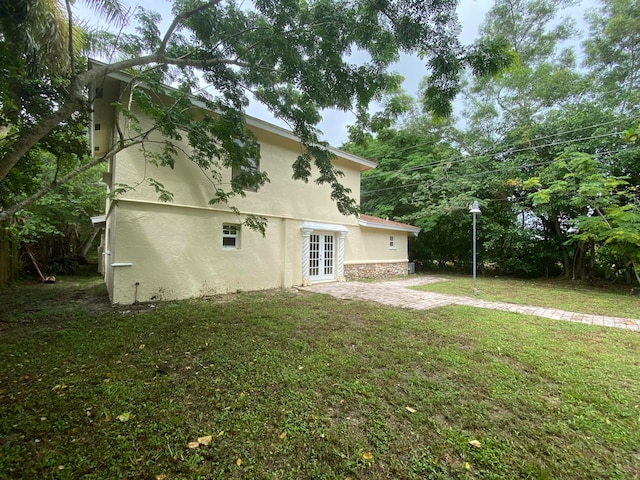 back of property featuring a lawn and french doors