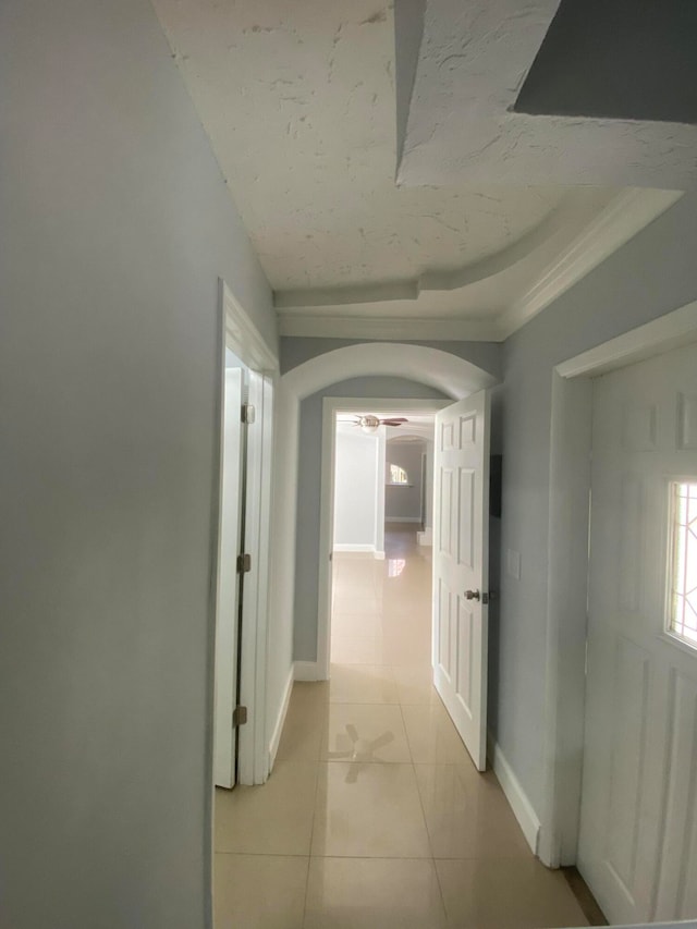 hall with a raised ceiling and light tile patterned floors