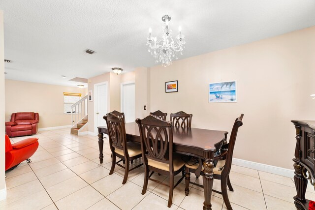 dining space featuring a textured ceiling, light tile patterned flooring, and a chandelier